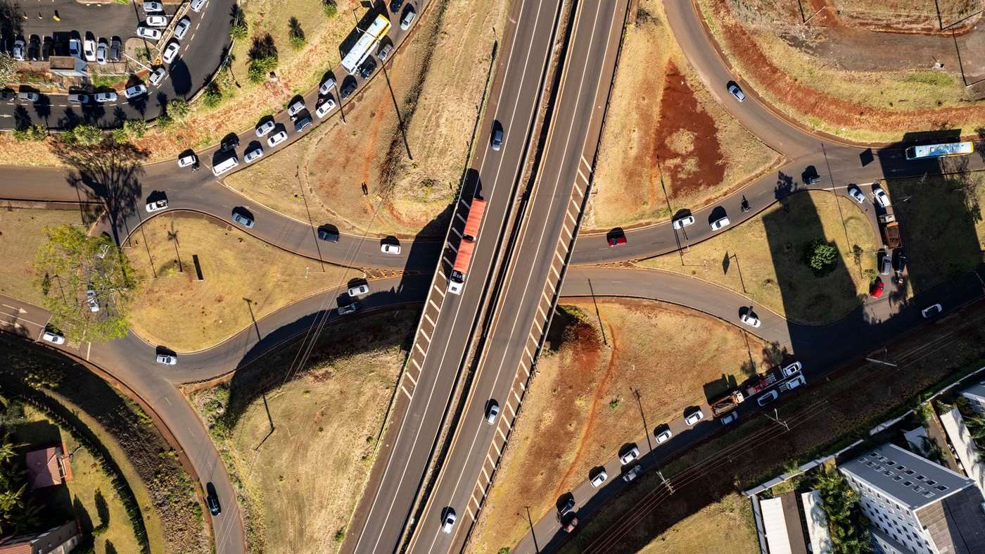 Trevo rodoviário visto de cima, com filas de carros nas alças