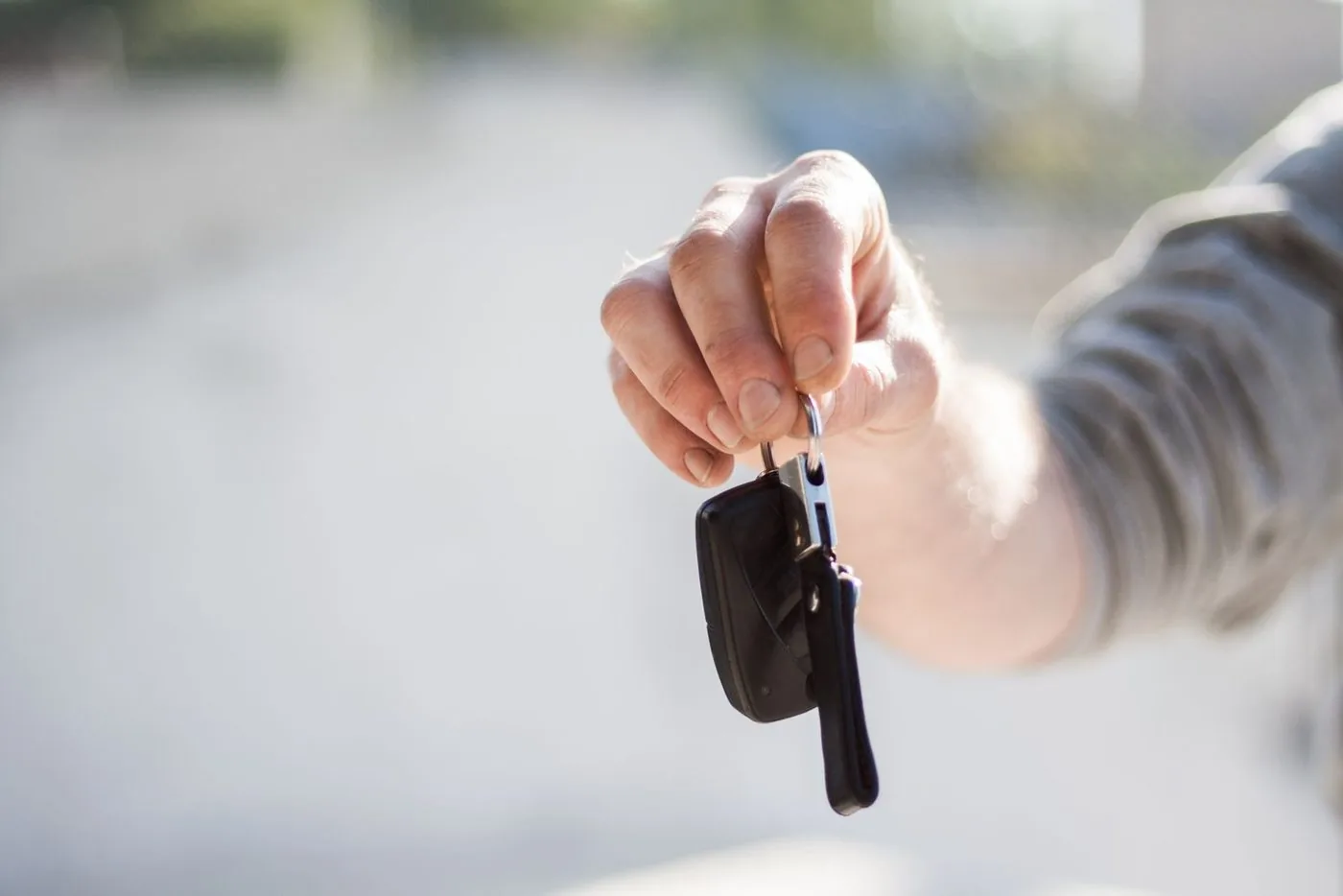 Mão estendida entregando a chave de um carro