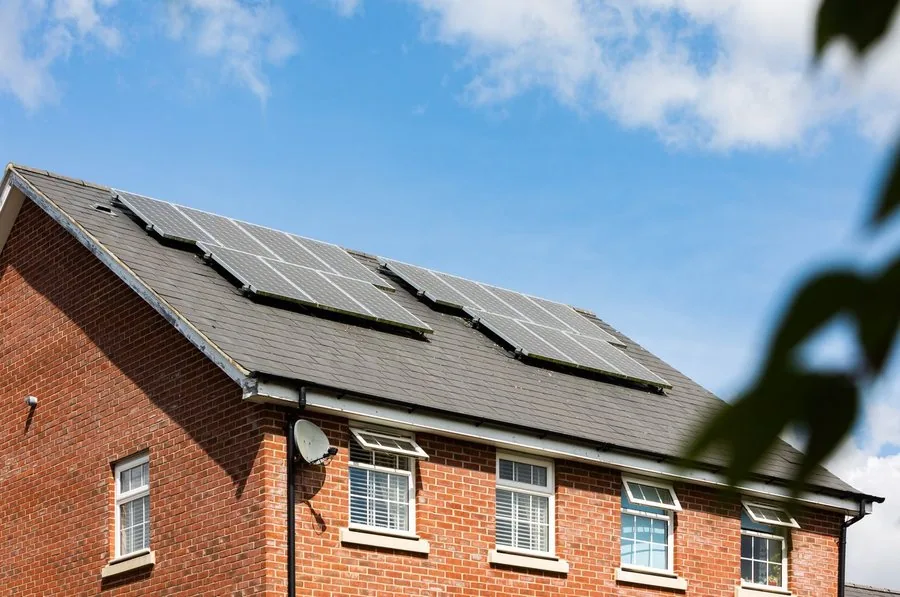 Placas solares no telhado de um prédio de tijolos