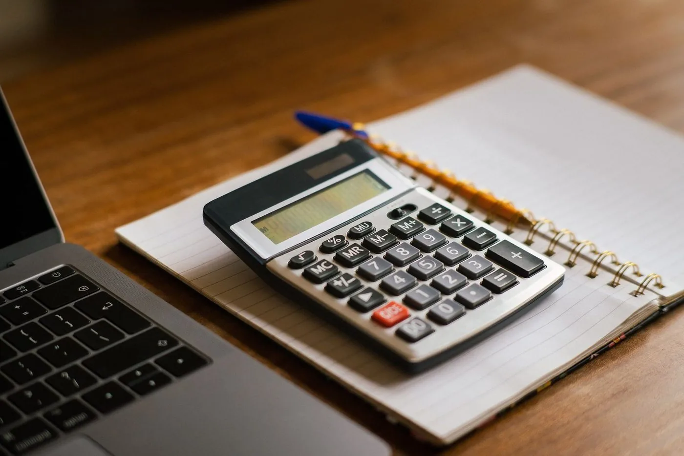 Calculadora sobre caderno pautado ao lado do notebook